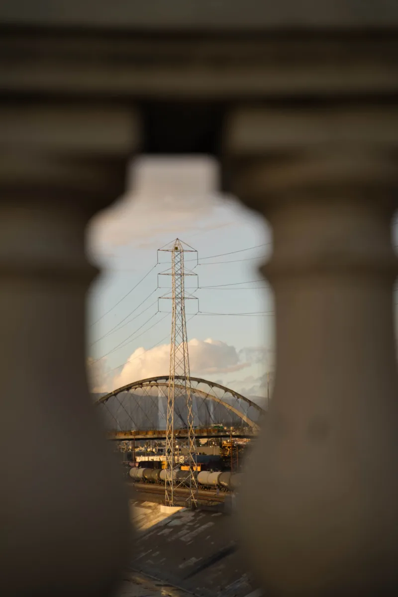 A transmission tower and arched bridge framed in the gap between two blurred stone balusters